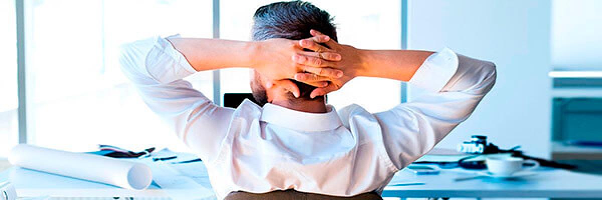 Financiación de importaciones - Un hombre con camisa sentado es su oficina mirando a la ventana con las manos en la cabeza Financiación de importaciones - Un hombre con camisa sentado es su oficina mirando a la ventana con las manos en la cabeza