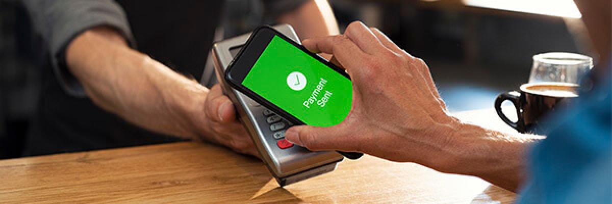 Servicio pago por movil - Persona pagando con su movil en el tpv de un comercio Servicio pago por movil - Persona pagando con su movil en el tpv de un comercio